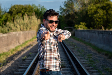 Hombre apuesto y sonriente señalando a cámara en expresión de confianza y buenos deseos