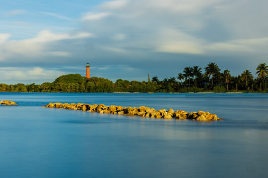long exposure of the jupiter lighthouse with houses and dock's removed taken from Dubois park in Jupiter Florida with rocks in the foreground.