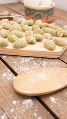 close up of raw spinach gnocchi on wooden board
