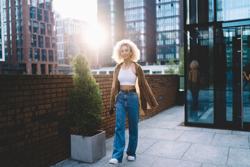 Positive ethnic female walking on city street