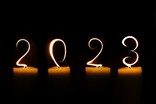 2023 written with candle flames on black background, new year greeting card
