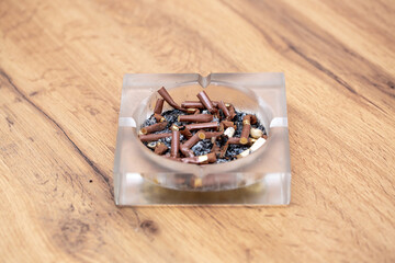 A lot of burnt cigarette butts with ashes in an ashtray close-up. The concept of the dangers of...
