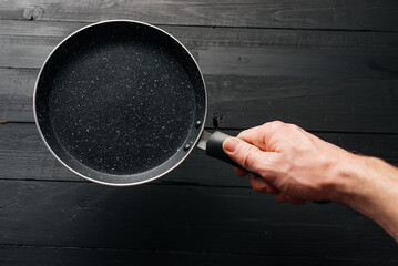 Empty pan in hand on black wood background