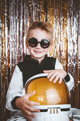 Portrait of funny child in fancy dress of astronaut pilot having fun in festive background with...