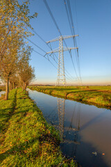 High voltage lines and pylons reflected in a Dutch polder landscape. The photo was taken in the...