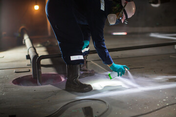 Fototapeta premium Male worker test spaying white contrast magnetic field test white contrast carbon bottom plate of storage tank oil