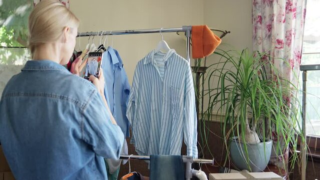 Woman taking picture of preowned shirt for resale on her smartphone, second hand clothes concept.