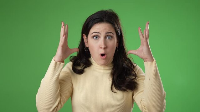 Pretty thinking young woman 20s, looks at camera gives mind blown gesture showing explosion of ideas posing on green screen background.