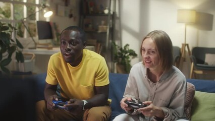 Young African American man and Caucasian woman playing video game on TV together at home