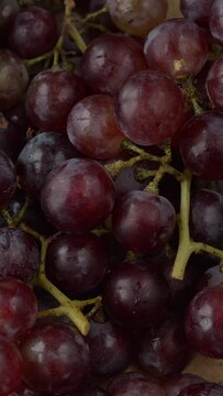 Close-up background texture view of garden grown grape fruits. Table spin. Vertical video.