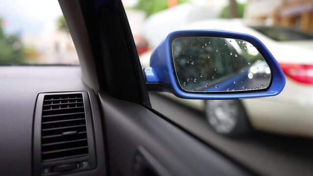 Slow motion video of a modern blue car right side mirror, while driving on a street.