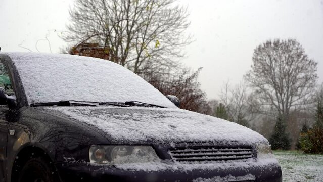 Car is covering with first snow. Snowing soft snowflakes on the car