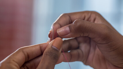Thread into the needle. Hands of woman pulling thread into the needle. a tailor threading a needle.