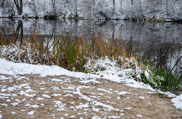 Winter landscape with the first snow on the river. Cloudy day.