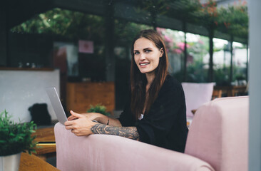 Smiling woman with laptop sitting in cafe
