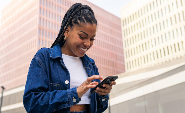 Black Woman Using Smartphone On City Street