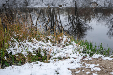 Winter landscape with the first snow on the river. Cloudy day.