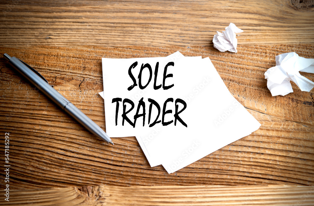 Poster sole trader text written on sticky on wooden background