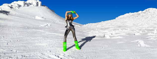 Sexy woman in silver cosmic outfit silver and winter boots is posing in the mountains. Female model...