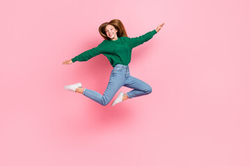 Full length photo of sweet adorable young lady wear green sweater jumping high arms sides isolated pink color background
