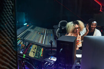 Diverse musicians working in recording studio on computer