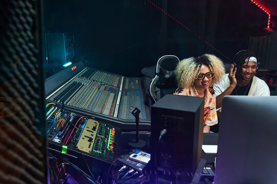 Diverse musicians working in recording studio on computer