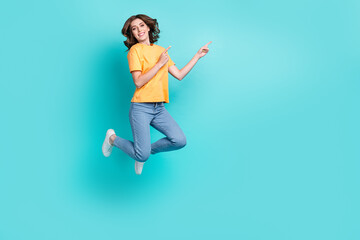 Fototapeta na wymiar Full length photo of pretty shiny lady wear yellow t-shirt jumping high pointing empty space isolated turquoise color background