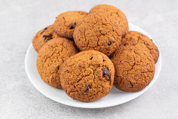 Oatmeal cookies in a white plate on a gray table.