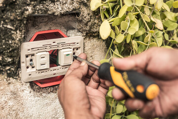 An electrician installs a new combo switch and outlet to an outdoor wall. A handyman doing...