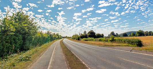 altocumulus floccus clouds over the highway. - obrazy, fototapety, plakaty