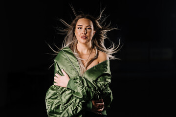 Portrait of young blond woman with blowing hair in front of black background