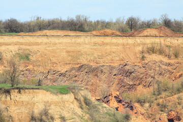 The rocky edge of the ground failed. Orange-red rock on the dip in the ground.