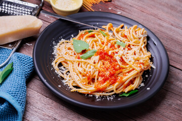 Delicious spaghetti pasta with prawns and cheese served in a black bowl on a black background table Italian recipe, tomato sauce, vegetables, and spices top view with copy space