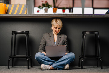 Business woman sitting on the floor with laptop under table