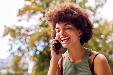 Smiling Young Woman Outdoors Laughing As She Talks On Mobile Phone