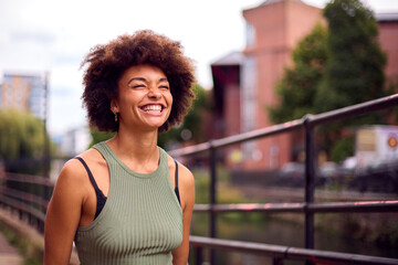 Fototapeta na wymiar Smiling Young Woman Outdoors Laughing As She Walks Through City