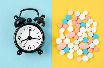 The alarm clock and many drug on a yellow background. Taking medicine at the right time concepts.