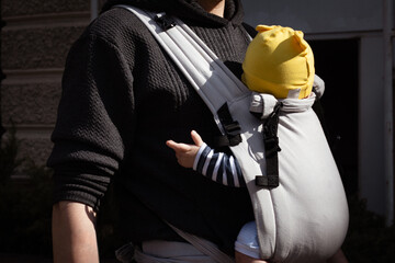 father carrying his child in a baby sling
