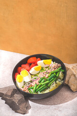 Rich fish salad bowl or poke with vegetables on the natural stones. Tuna, potatoes, avocados, eggs, tomatoes, green beans. Healthy dinner, lunch, Earth tones, eco friendly. Natural cuisine concept