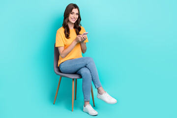 Full length photo of cute sweet lady wear yellow t-shirt typing modern device empty space sitting...