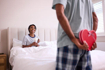 Loving Man Surprising Woman With Romantic Box Of Chocolates In Bedroom