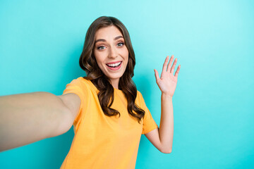 Photo of cheerful nice lady wear yellow stylish outfit arm waving tell hi rejoice see friend empty space isolated on cyan color background © deagreez