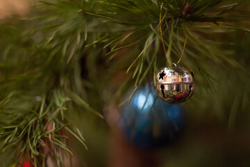 New Year's toy on a spruce branch Christmas golden round bell with stars with a blurred background