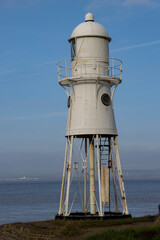 Lighthouse tower by the sea with coast and clouds