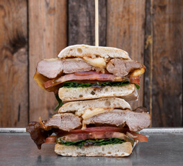 Gourmet sandwich. Closeup view of a multilayer sandwich with ciabatta bread, bondiola, cheese,...