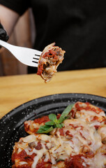 Stuffed pasta. Closeup view of a hand holding a fork, eating sorrentinos stuffed with cherry tomatoes and veal, with a mediterranean sauce and provolone cheese. 