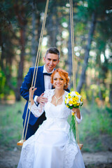 Young beautiful couple in a blue suit and white wedding dress with a bouquet