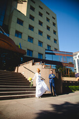 Obraz premium Young beautiful couple in a blue suit and white wedding dress with a bouquet