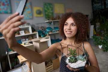 Successful young female florist posing for a selfie with plants