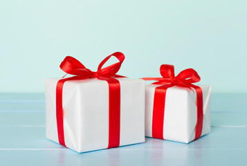Gift boxes with red ribbon bow on color background